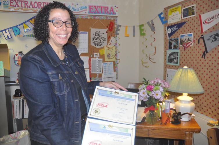 Badger High School teacher Deanna Giovingo holds up two state awards that she recently received