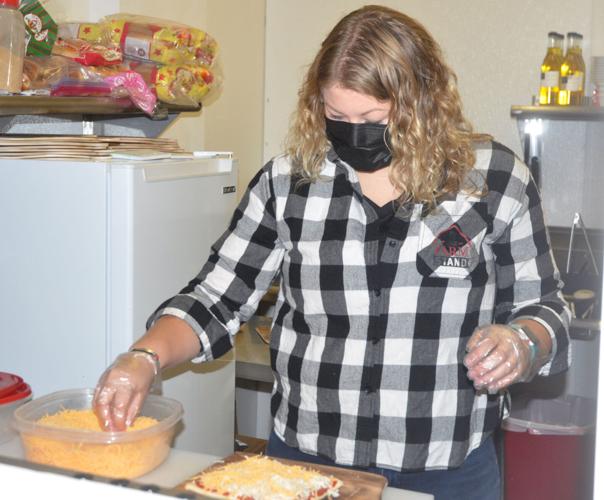 Danielle Robers adds some ingredients to a pizza that she is baking at her parents' business