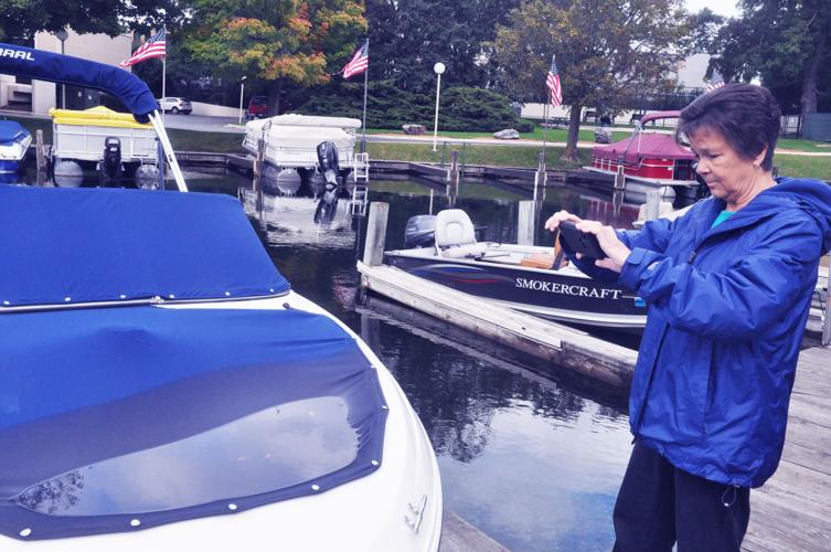 Harbormaster Linda Frame takes photographs of a boat cover that has been covered with water