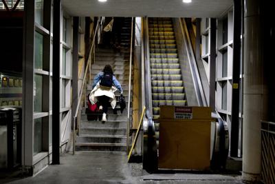 A woman carries a suitcase up the stairs next to a broken escalator at the Hamilton Train Station on Feb. 6, 2025, in Hamilton, N.J.