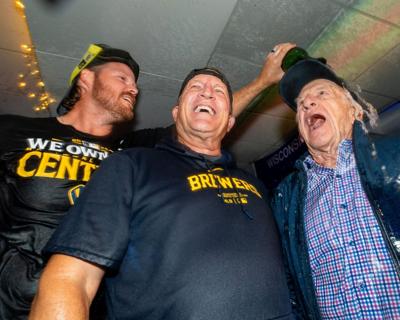 Brewers pitcher Brandon Woodruff pours champagne on broadcaster Bob Uecker, right, and manager Pat Murphy after the team