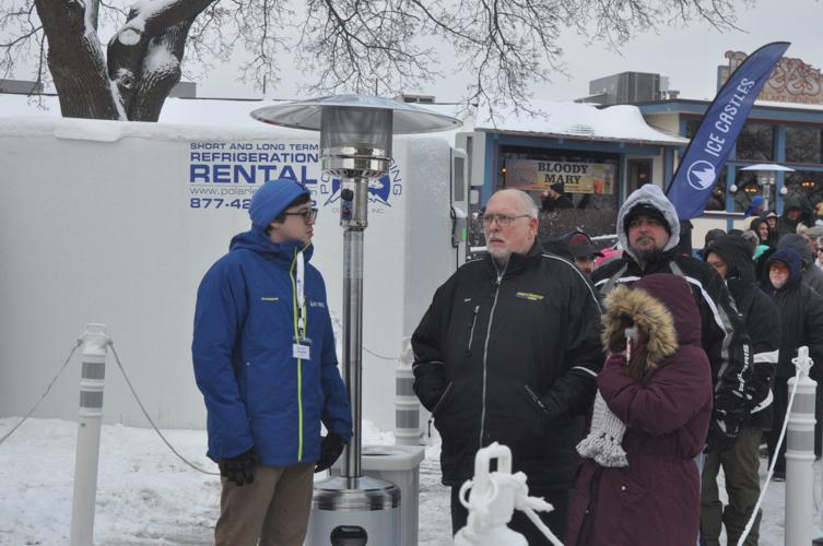 A crowd of people line up as they wait to enter the ice castle during its opening day.