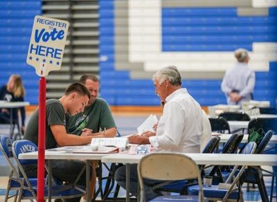 Poll workers, right, assist with voter registration during the Wisconsin partisan primary election on Tuesday, August 11, 2026, at the Brookfield Central High School polling station in Brookfield, Wisconsin.