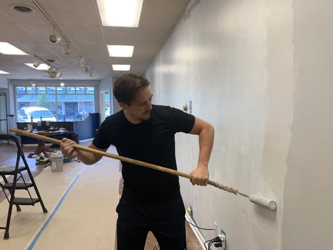 Tyler Dempsey, owner of Holistic Connections, does some painting work to his business Holistic Connections