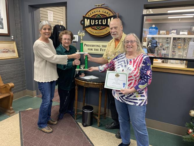 Geneva Lake Museum Executive Director Janet Ewing presents a traveling trophy to the Pete's Printing team