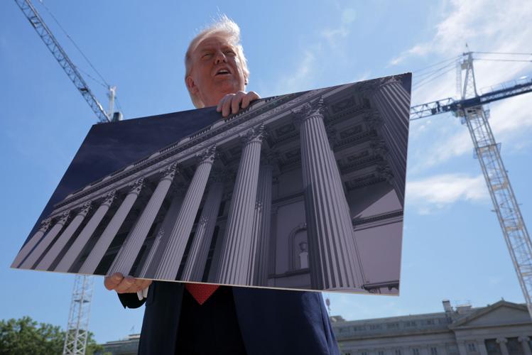 U.S. President Donald Trump holds artists' renderings as he talks to reporters about his proposed White House ballroom next to the worksite on May 19, 2026, in Washington, D.C..