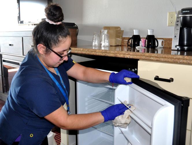Vanessa Flores, Harbor Shores hotel worker, cleans a refrigerator in a guest room of the hotel