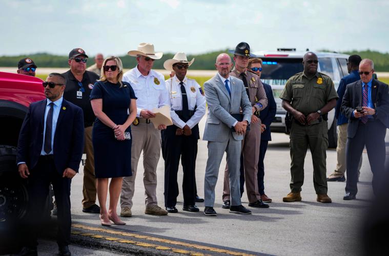People look on as Governor Ron DeSantis holds a press conference at Alligator Alcatraz in Ochopee, Fla., on Thursday, June 25,