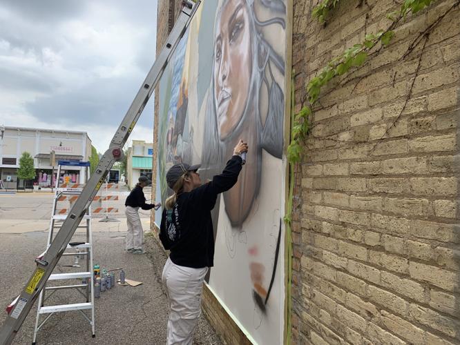 South Carolina residents Allison Dunavant and Christine Crawford paint a mural on the north-facing wall of 234 Broad St.
