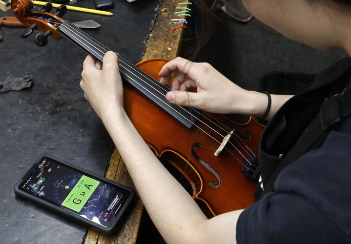 Intern repair technician Ayano Osawa tunes a violin