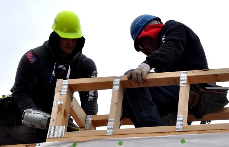 Crews from Balsitis Contracting begin working on the roof of a two-story building