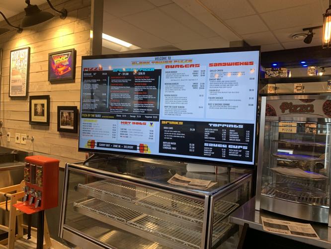 An electronic menu board lists some of the items that Clock Tower Pizza offers