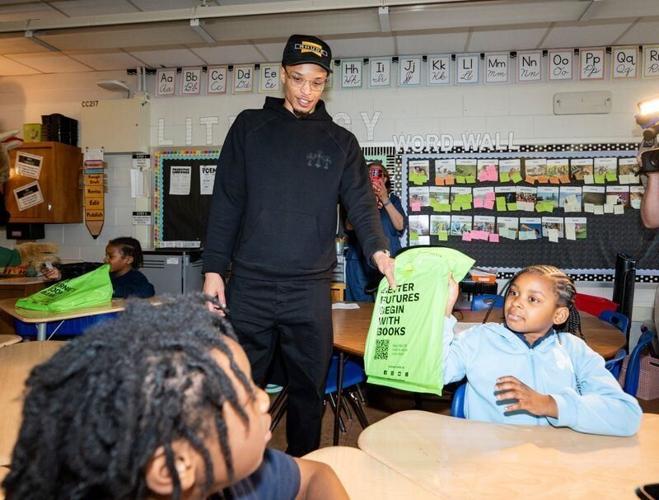 Milwaukee Bucks guard Ryan Rollins distributes a bag of books to third grader Sawah Mohamed at George Washington Carver Academy during an event with Bernie’s Book Bank on Wednesday May 13, 2026 in Milwaukee, Wisconsin.
