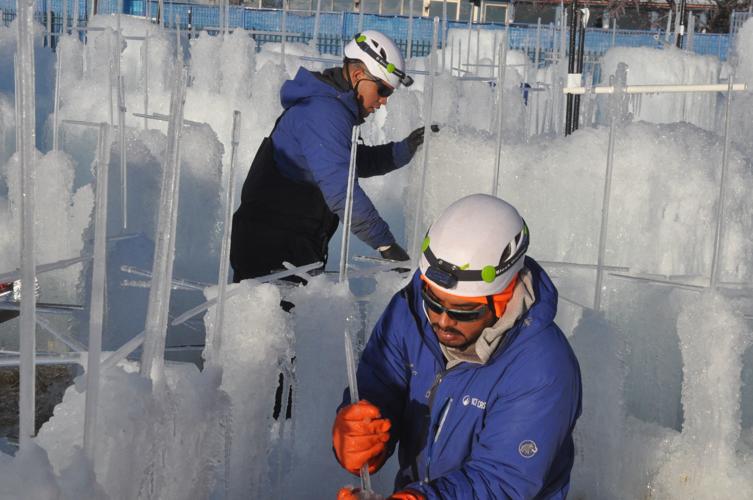 Juan Noreno of Lake Geneva puts some icicles in place while working on the Ice Castle structure.