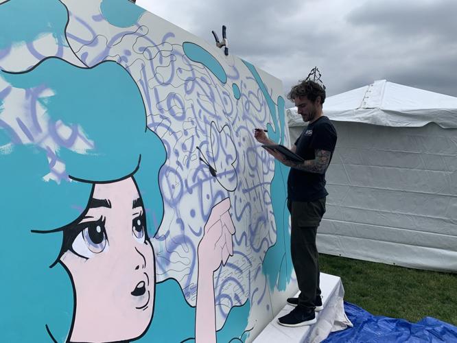 Daniel Broughan works on an interactive mural at Flat Iron Park
