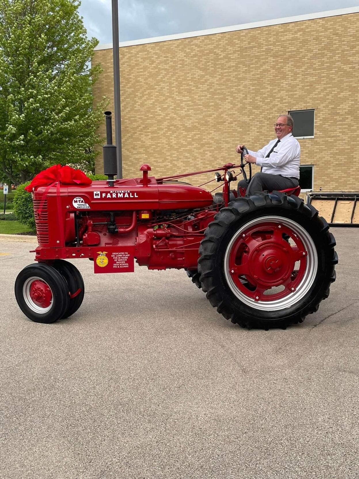Larry Plapp is all smiles as he rides around on a restored tractor presented to him by his students