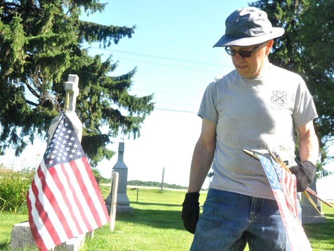 Tim Walters, St. Francis de Sales Cemetery Committee member, prepares to install some flags