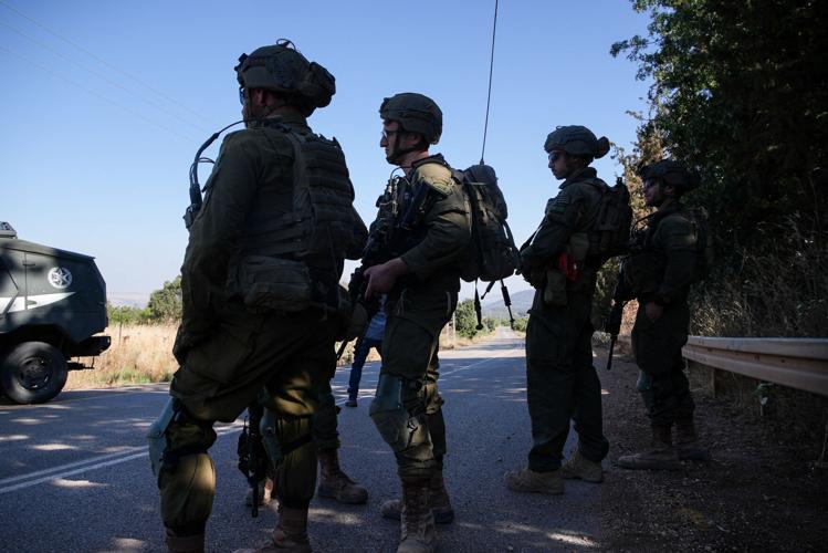 Israeli soldiers wait on a road, after the Israeli military said it killed one person in an incident in which they returned fire, by the Israel-Lebanon border in northern Israel
