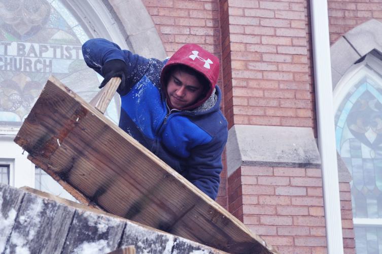 Alejandro Valdez discards a large piece of the Geneva Village Shops' porch