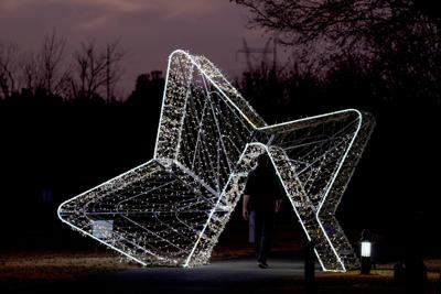 A person walks under a holiday light display at Edmond Electric's Luminance at Mitch Park, Wednesday, Dec. 17, 2025.