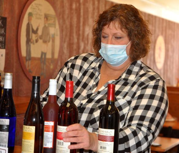 Roberta Robers, co-owner of The Farmstand, looks over some bottles of wines that she plans to offer