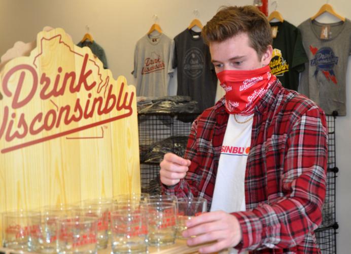 Dillon Murphy, Drink Wisconsinbly employee, looks over some of the shot glasses that are sold at the store