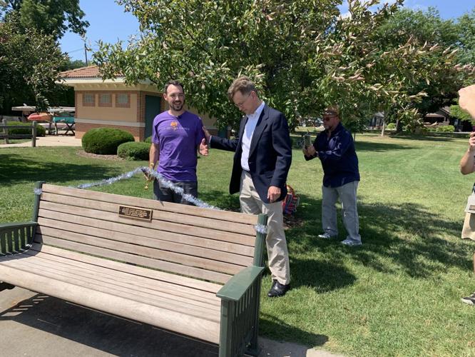 Alex Gygax, son of Gary Gygax, cuts the ribbon to the Gygax Park bench with a ceremonial sword
