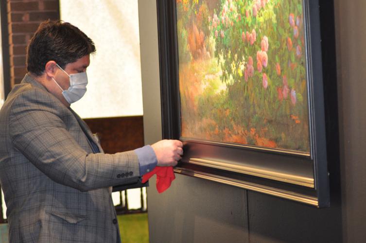 Dari Nateghi, co-owner of Noure's Oriental Rug Gallery, dusts off a painting at his business's new location in Fancy Fair Mall