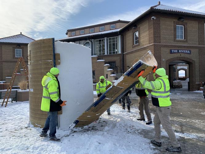 City crews pull a part a large cylinder to reveal a snow block