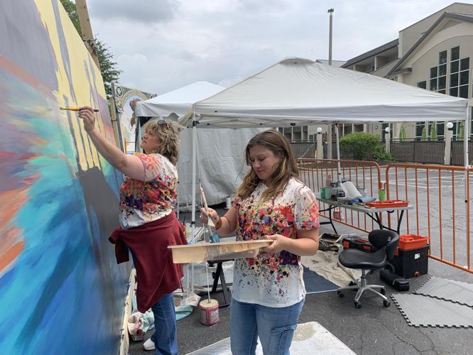 Sabrina Roddy and Freybrianne Ziervogel work on a mural in the parking lot of Lake City Social