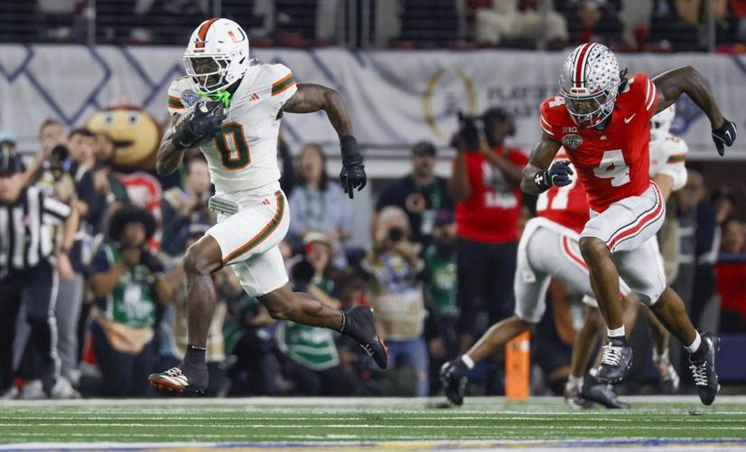 Miami Hurricanes defensive back Keionte Scott intercepts the ball as Ohio State Buckeyes wide receiver Jeremiah Smith gives chase during the first half of the College Football Playoff quarterfinal game in the Cotton Bowl at AT&T Stadium in Arlington, Te...