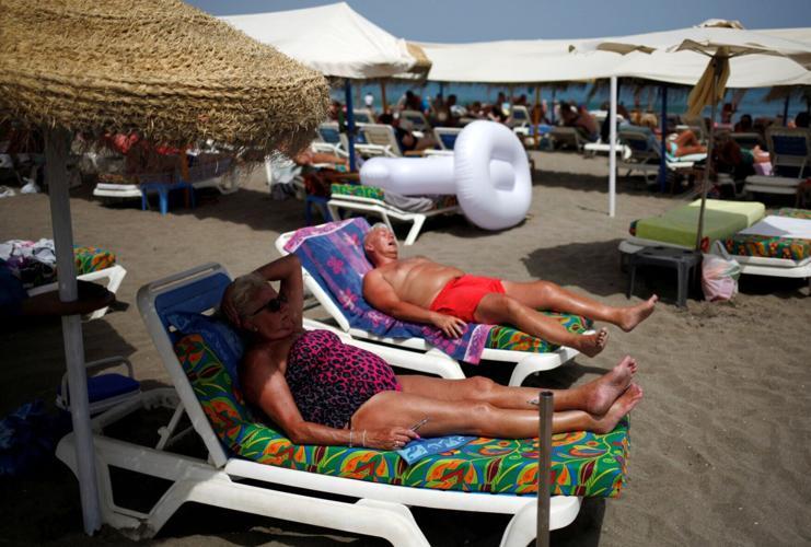FILE PHOTO: Tourists sunbathe on La Carihuela beach on a hot summer day during the first weekend of the summer in Torremolinos