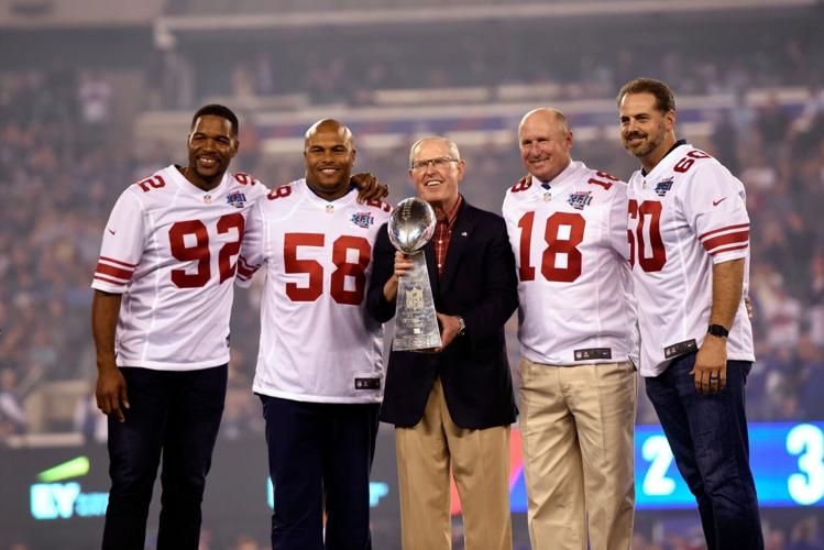 Representing the New York Giants team that won the 2007-season Super Bowl XLII are, from left, Michael Strahan, Antonio Pierce, head coach Tom Coughlin, Jeff Feagles, and Shaun O'Hara, standing on the stage during a ceremony as the Giants played the Det...