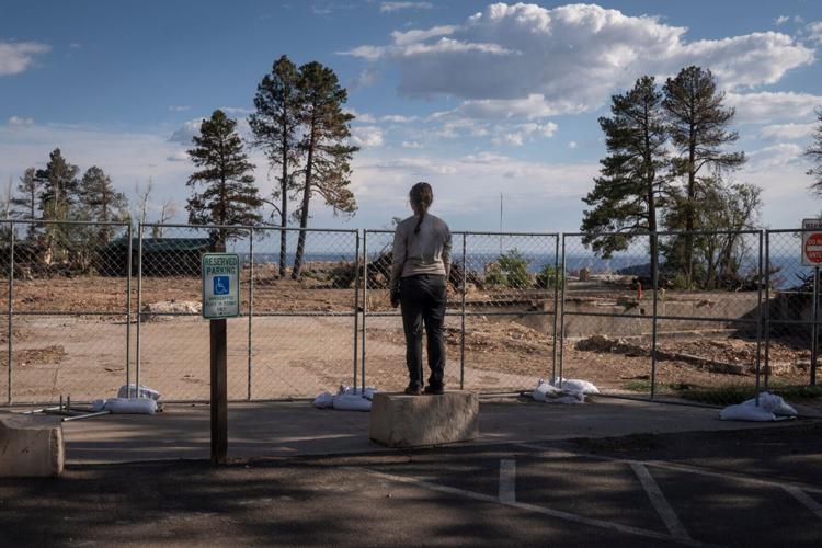 Megan Quinn views the burned-down Grand Canyon Lodge from behind a fence at the North Rim of the Grand Canyon on June 17, 2026.