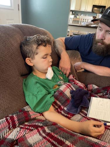 Jonah Reynolds sits with his father in May 2022 after a doctor extracted a tooth that caused him severe pain.