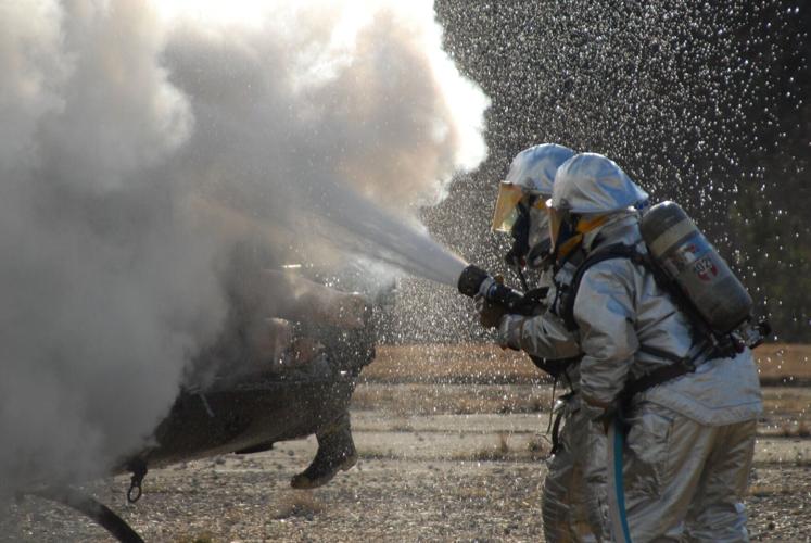 Firefighters spray PFAS-laden foam to put out a helicopter fire during a training exercise in 2007. Firefighting foams form a "blanket" over liquid fuel that helps extinguish fires quickly. The Pentagon has extended its deadline to stop using the foam to O