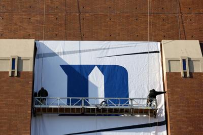INDIANAPOLIS, IN- APRIL 01: Workers hang the Duke Blue Devils logo on the side of Lucas Oil Stadium home of the 2015 Final Four on April 1, 2015 in Indianapolis, Indiana.