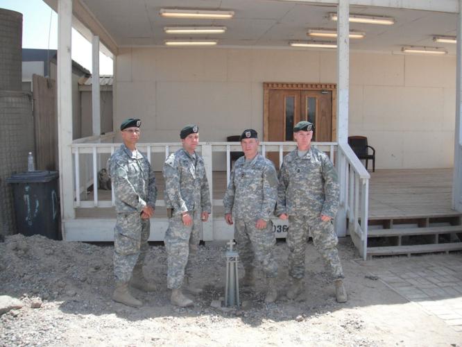 Ron Bucca Jr., (second from left) joined three Green Berets who served with his father in the Army's Special Forces at Camp Bucca, Iraq in 2011. They are standing next to a cross fashioned from steel recovered from the World Trade Center after the 9/11 att