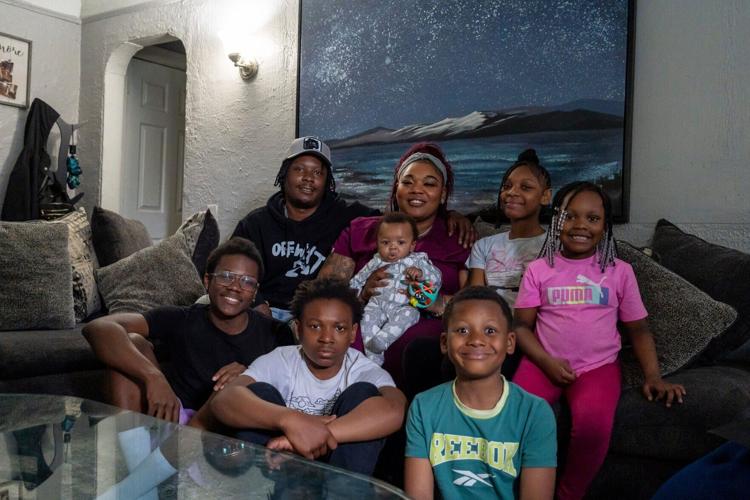 Rakiah Reives, 33, a certified nursing assistant, takes a family photo with her husband and kids inside their home in Detroit on Tuesday, May 5, 2026. Reives is one of several mothers receiving cash payments through the Rx Kids program, which aims to ease