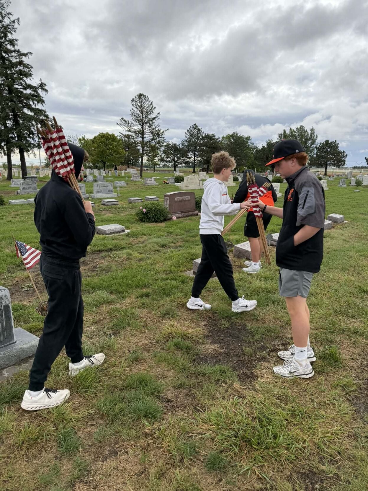 Lexington baseball teams place flags for Veterans at Lexington cemeteries
