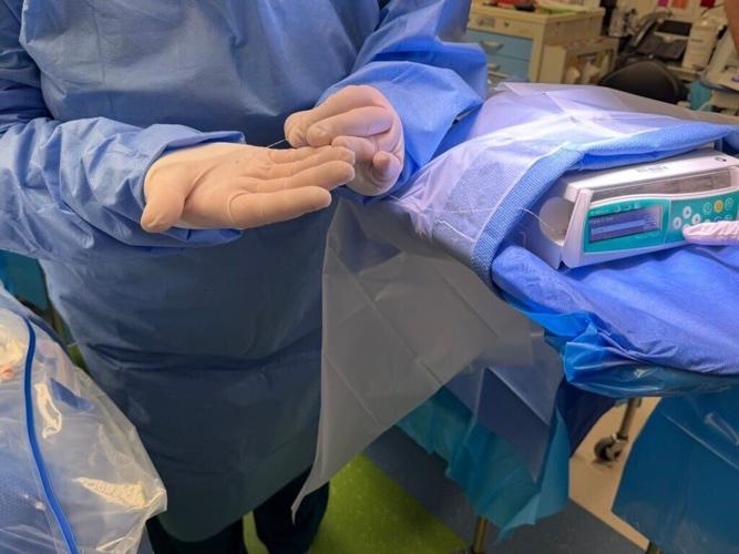 Jennifer Schmid, surgical technologist at Children’s Wisconsin, holds the catheter used during a procedure to deliver a newly approved gene therapy into the ears of the Plumb sisters on July 20 in Milwaukee. The therapy is infused directly to reach the c