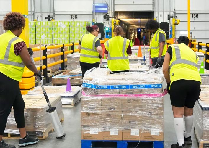 Amazon employees unload packages from a truck at the loading station of the company's facility at 2501 N. Normandy Blvd. in