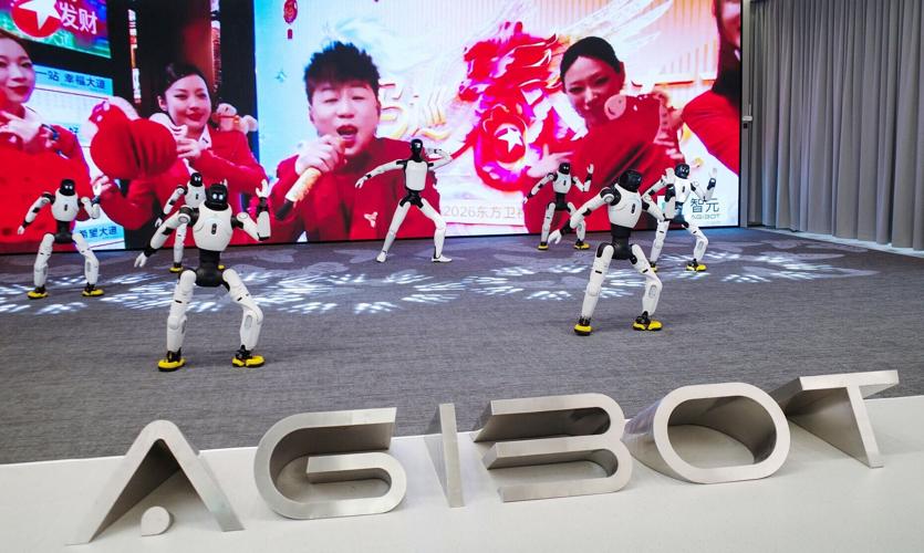 Agibot humanoid robots dance in front of a giant screen at the company's headquarters in Shanghai