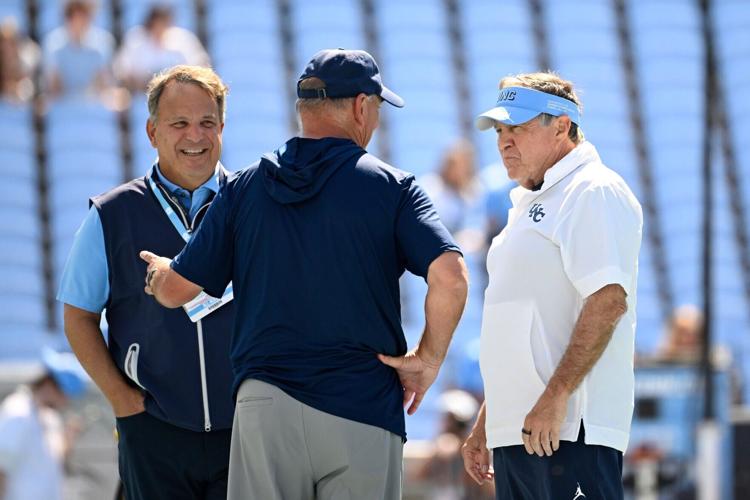 Sep 13, 2025; Chapel Hill, North Carolina, USA; Richmond Spiders head coach Russ Huesman talks to North Carolina Tar Heels general manger Michael Lombardi and head coach Bill Belichick before the game at Kenan Stadium. Mandatory Credit: Bob Donnan-Imagn Im