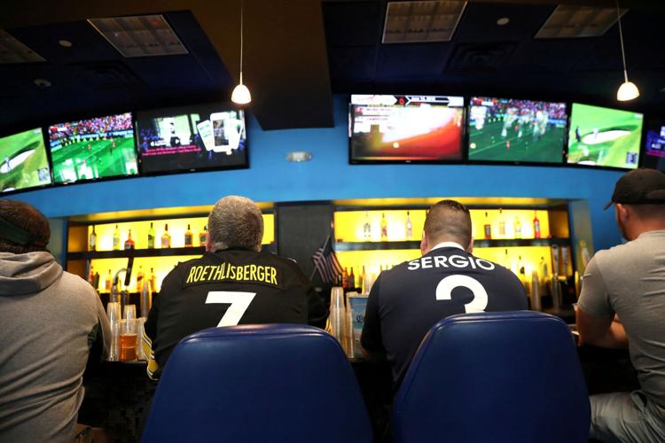 FILE PHOTO: Gamblers watch sports on televisions at Monmouth Park Sports Book by William Hill, shortly after the opening of the first day of legal betting on sports in Oceanport