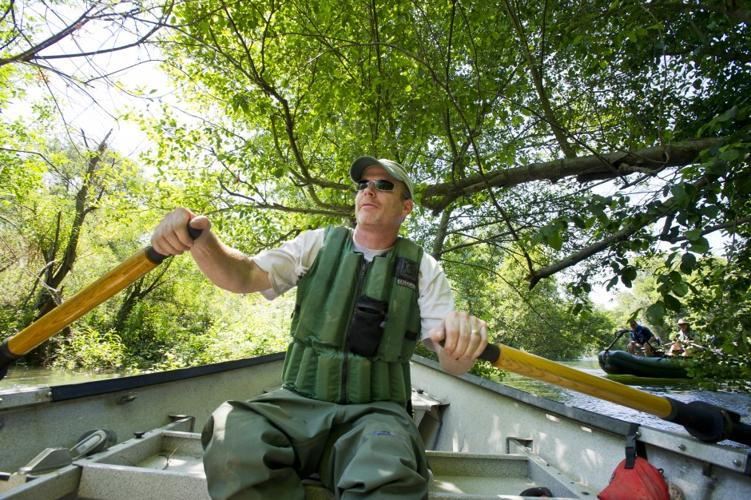 A Man Sitting And Fishing Leisurely By A Pool In A River Stock