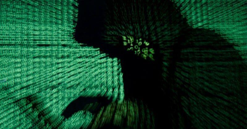 FILE PHOTO: Man holds laptop computer as cyber code is projected on him in this illustration picture