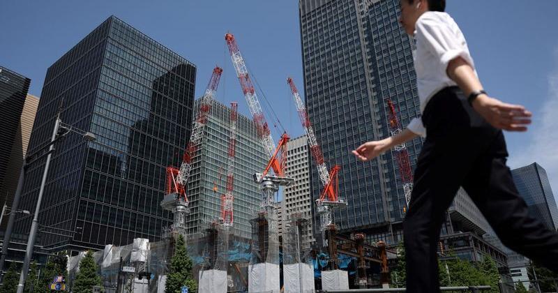 A man walks past on the street near a construction site in Tokyo