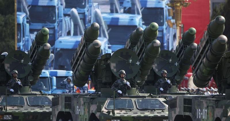 Soldiers stand in PLA rocket launcher trucks they rumble past Tiananmen Square in a parade in Beijing