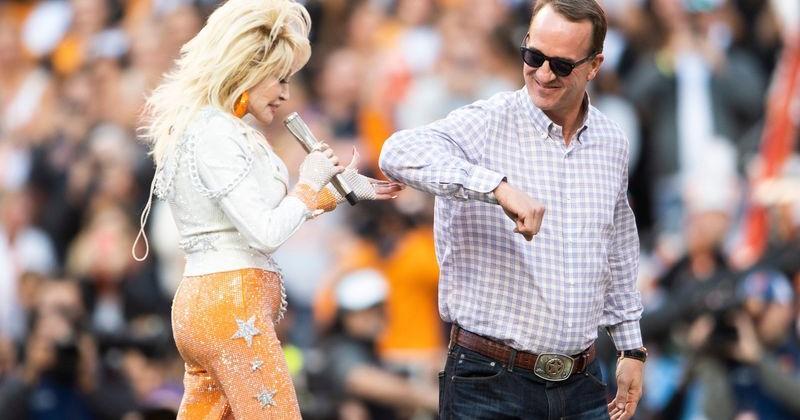 Dolly Parton is escorted off the stage by Peyton Manning after performing Rocky Top with the Pride of the Southland Band at the end of the first quarter of a football game between Tennessee and Georgia at Neyland Stadium in Knoxville, Tenn., on Saturday, Nov. 18, 2023.